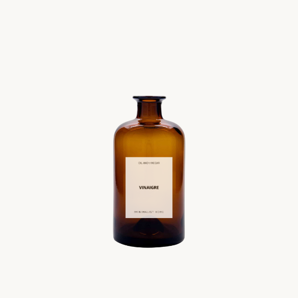 Duo de bouteilles en verre ambré avec bec verseur doré et noir, posées sur un plateau en bois, ambiance cuisine minimaliste et fonctionnelle.