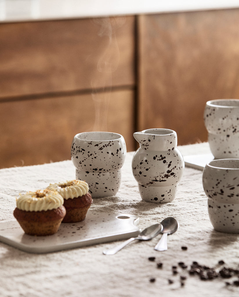 Pichet RIA en céramique de 300 ml avec motif splash, au style artisanal et élégant, posé sur une nappe en lin naturel.