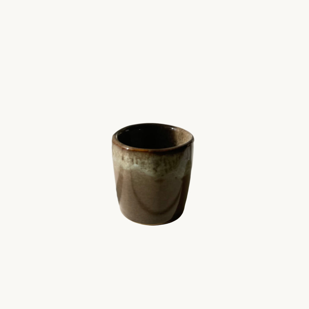 Tasse à expresso en grès brut finition mate, posée sur une table en bois clair, ambiance artisanale et épurée.